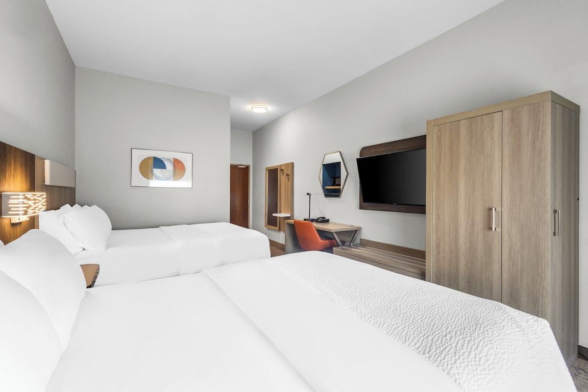 Habitación de hotel con dos camas, un escritorio, un televisor y un armario.