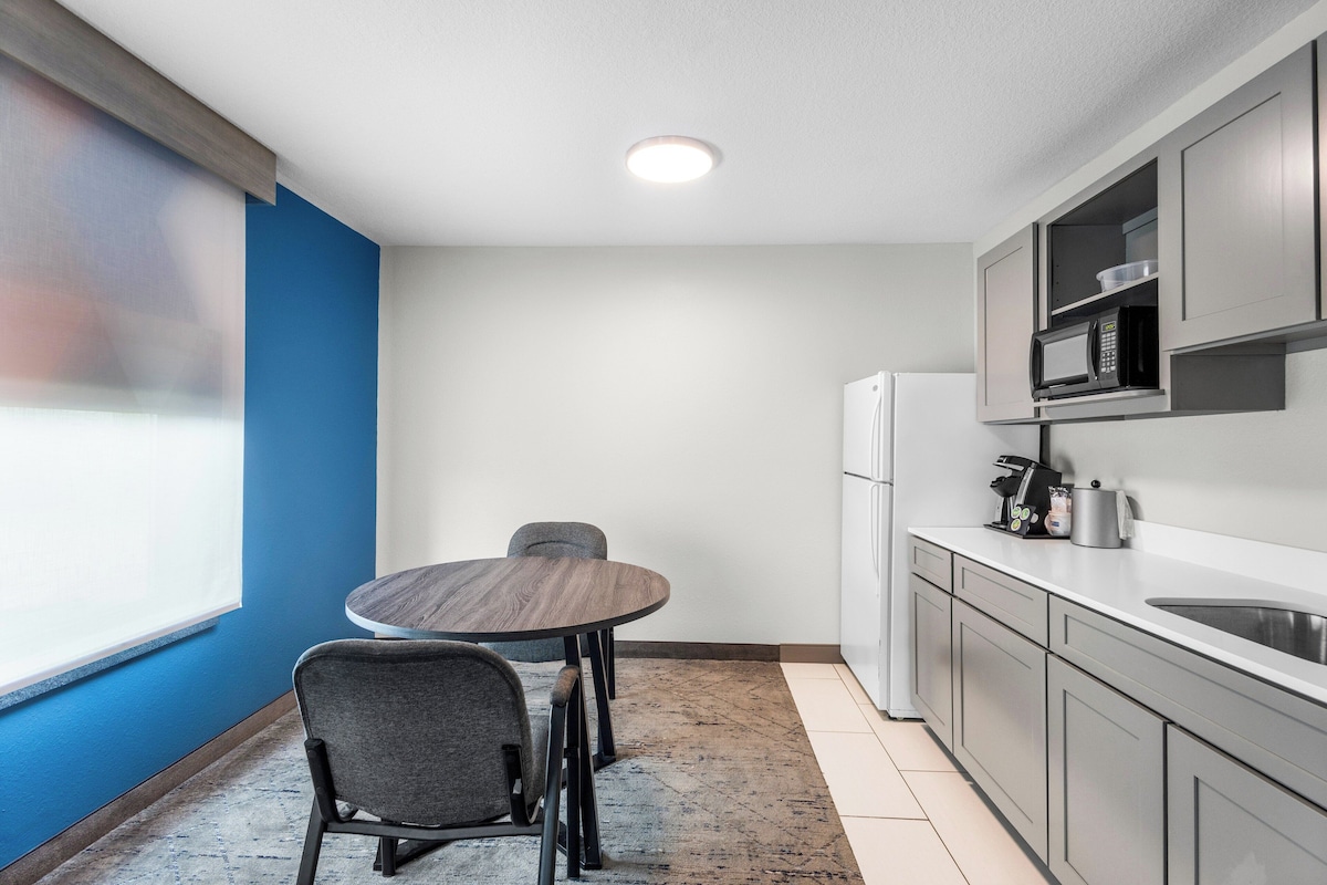 Una cocina funcional con una mesa de comedor y sillas, un refrigerador y un microondas.