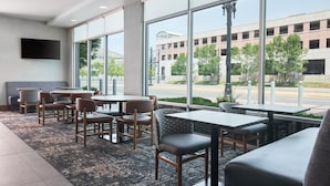 A modern restaurant with large windows, wooden tables, and cushioned seating. - Hyatt Place Salt Lake City/Downtown/The Gateway (Salt Lake City)