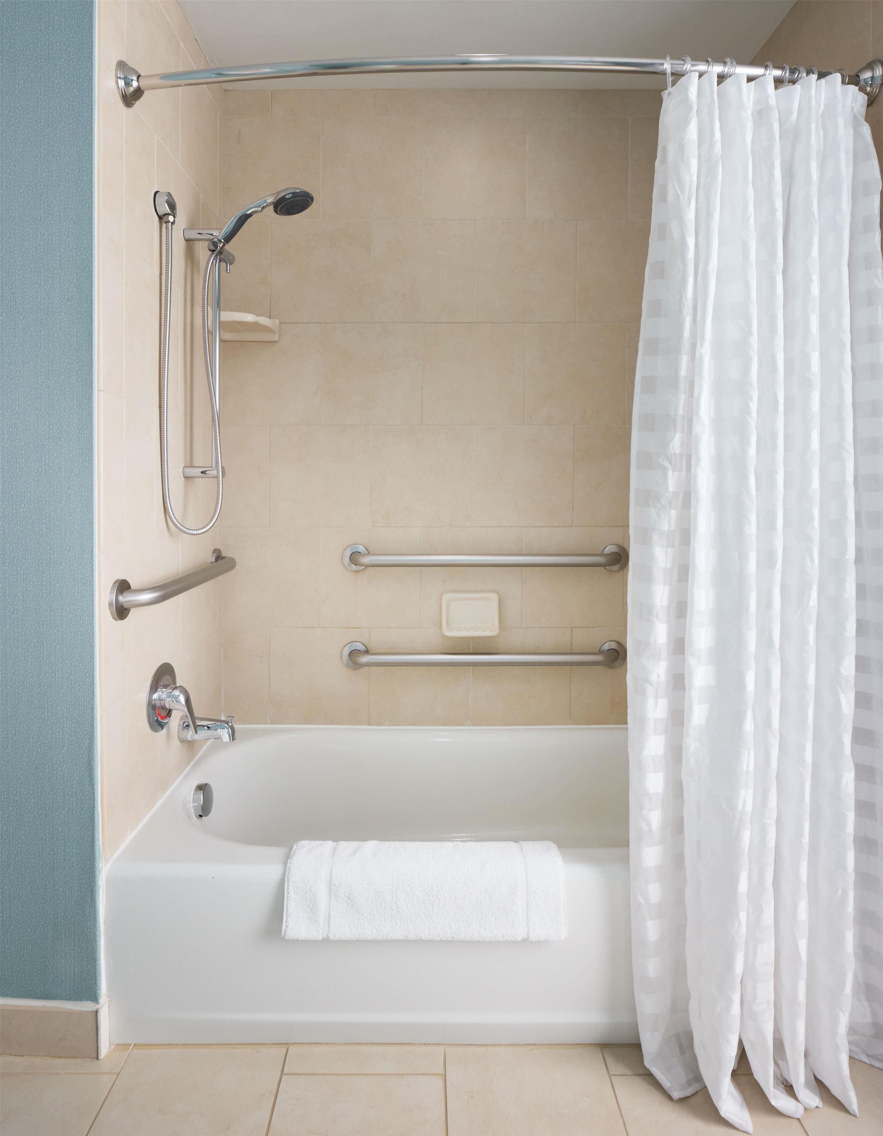 A modern bathroom with a bathtub, shower, and grab bars.