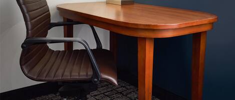 Una mesa de conferencias con una lámpara moderna, una silla de oficina de cuero y piso alfombrado.