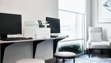 Un espacio de oficina moderno con un escritorio, dos monitores, una impresora y una silla.