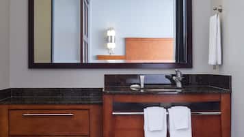A modern bathroom with a large mirror, wooden vanity, two sinks, and a towel rack.