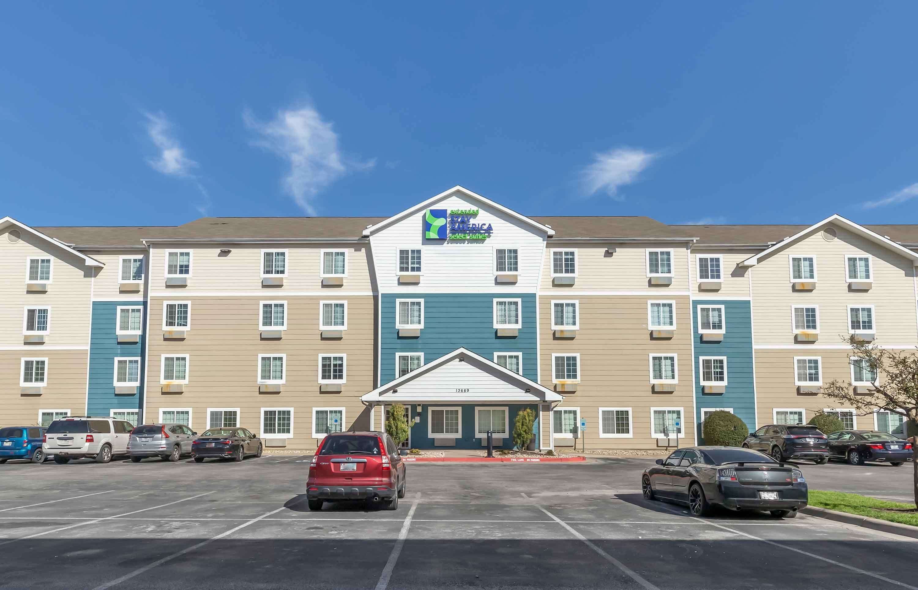 A multi-story hotel with a central entrance and a parking lot.