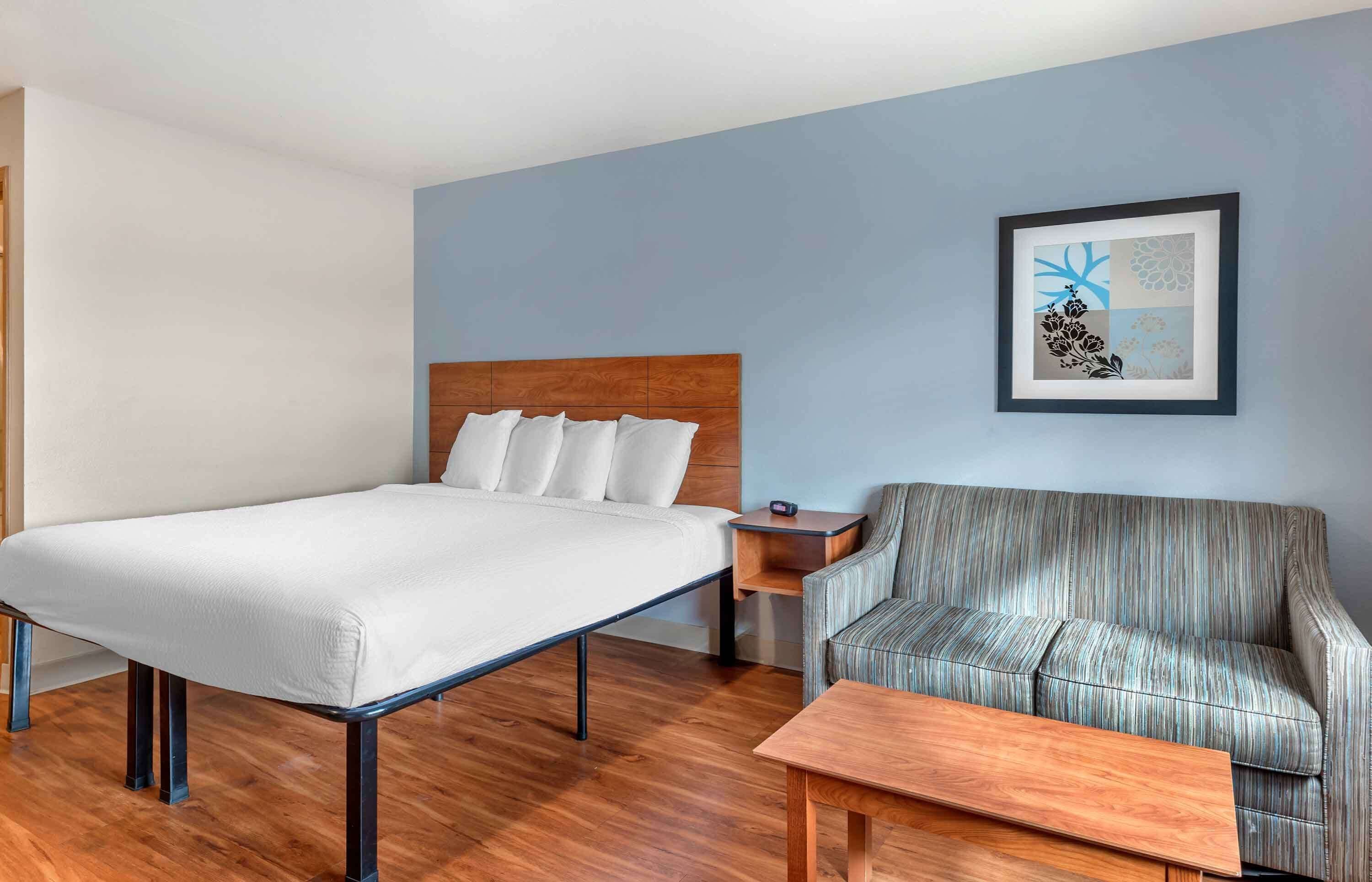 Une chambre d’hôtel avec un lit, un canapé, une petite table et un tableau encadré au mur.