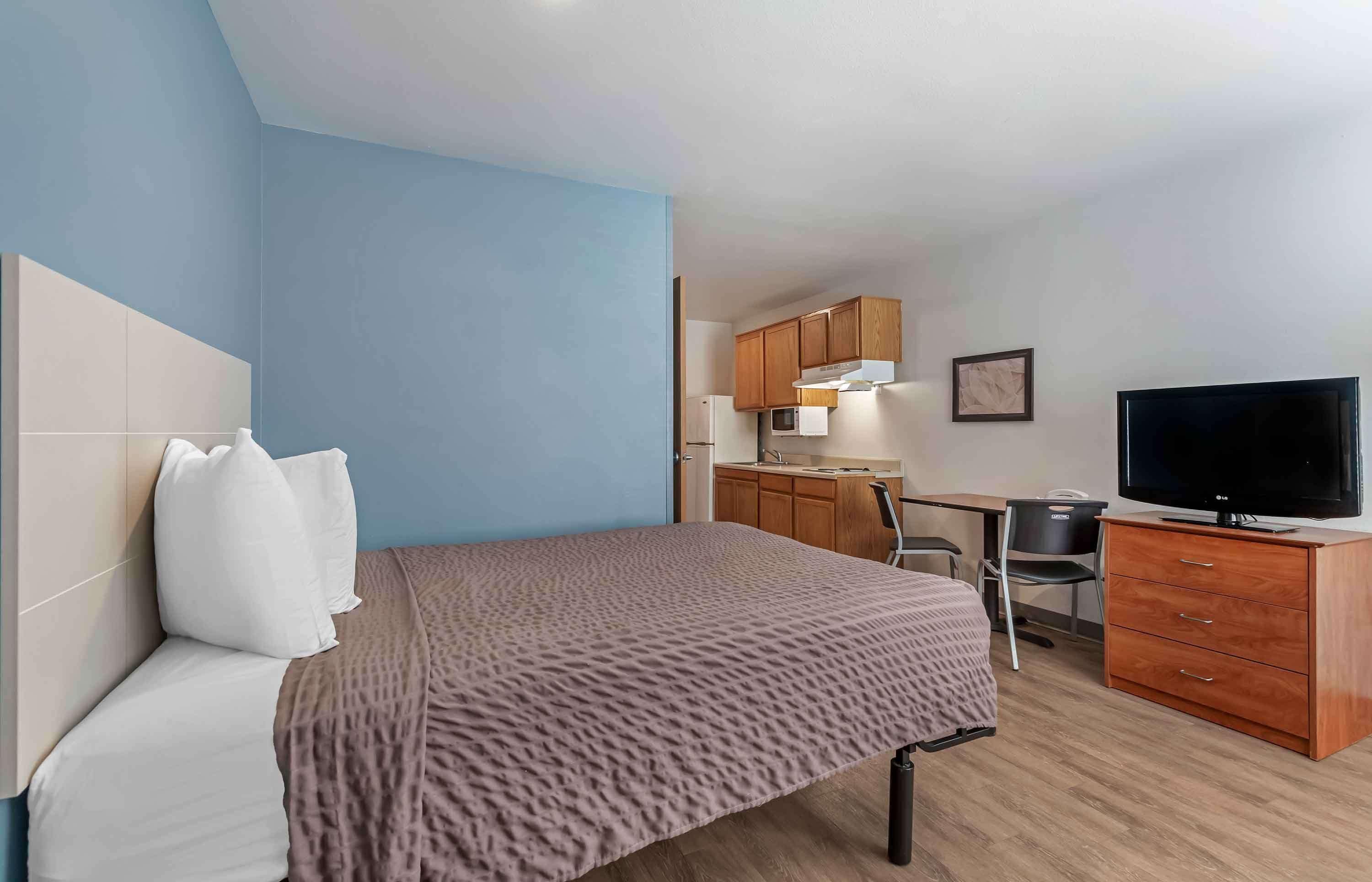 Une chambre d’hôtel équipée d’un lit, d’un bureau, d’une télévision et d’une kitchenette.