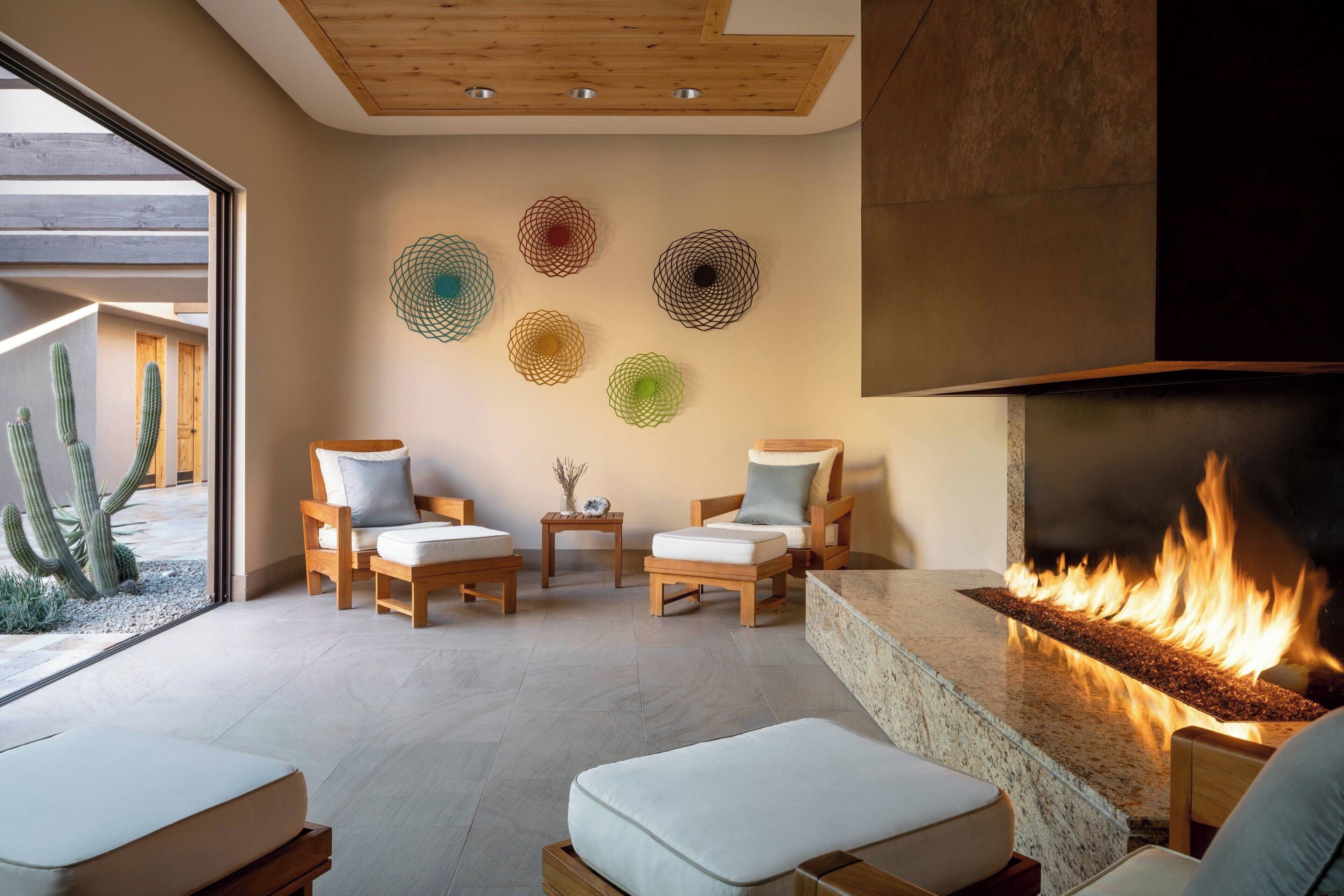 A modern lounge area with a stone fireplace, wooden furniture, and decorative wall art.