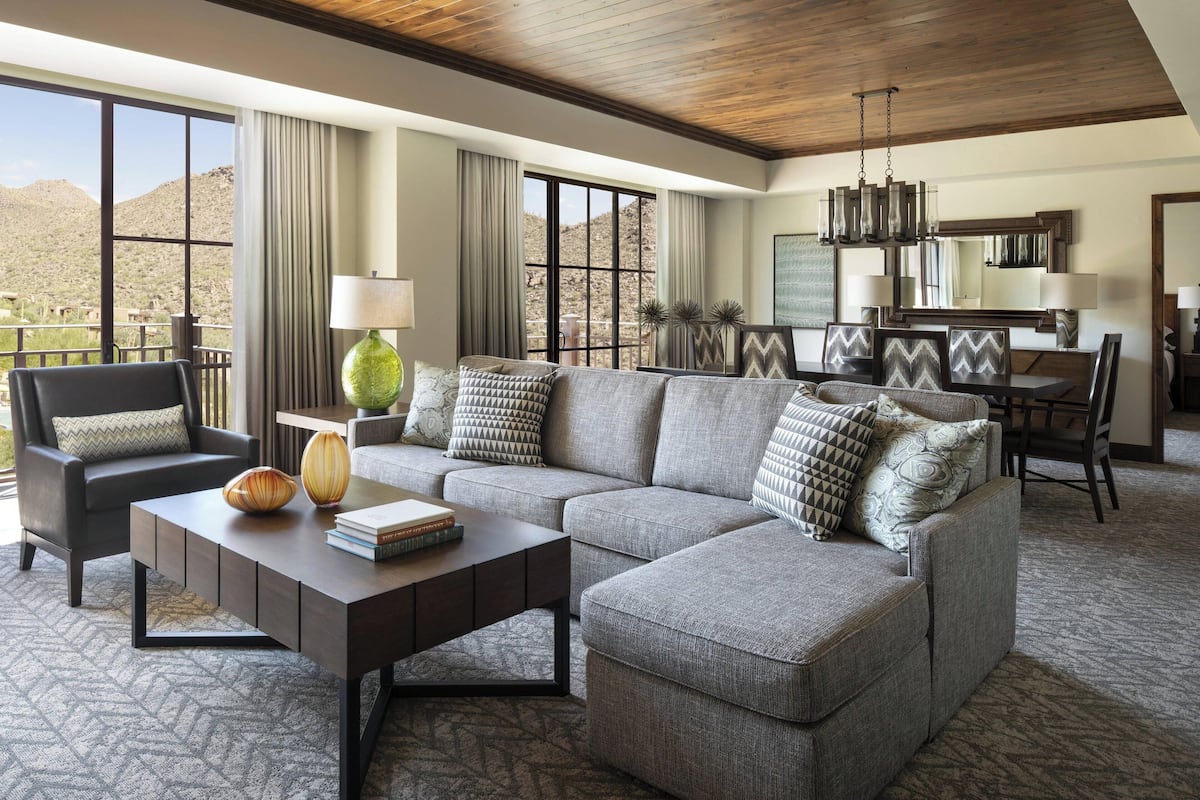 A modern living room with a sectional sofa, a coffee table, and a dining area with a chandelier.