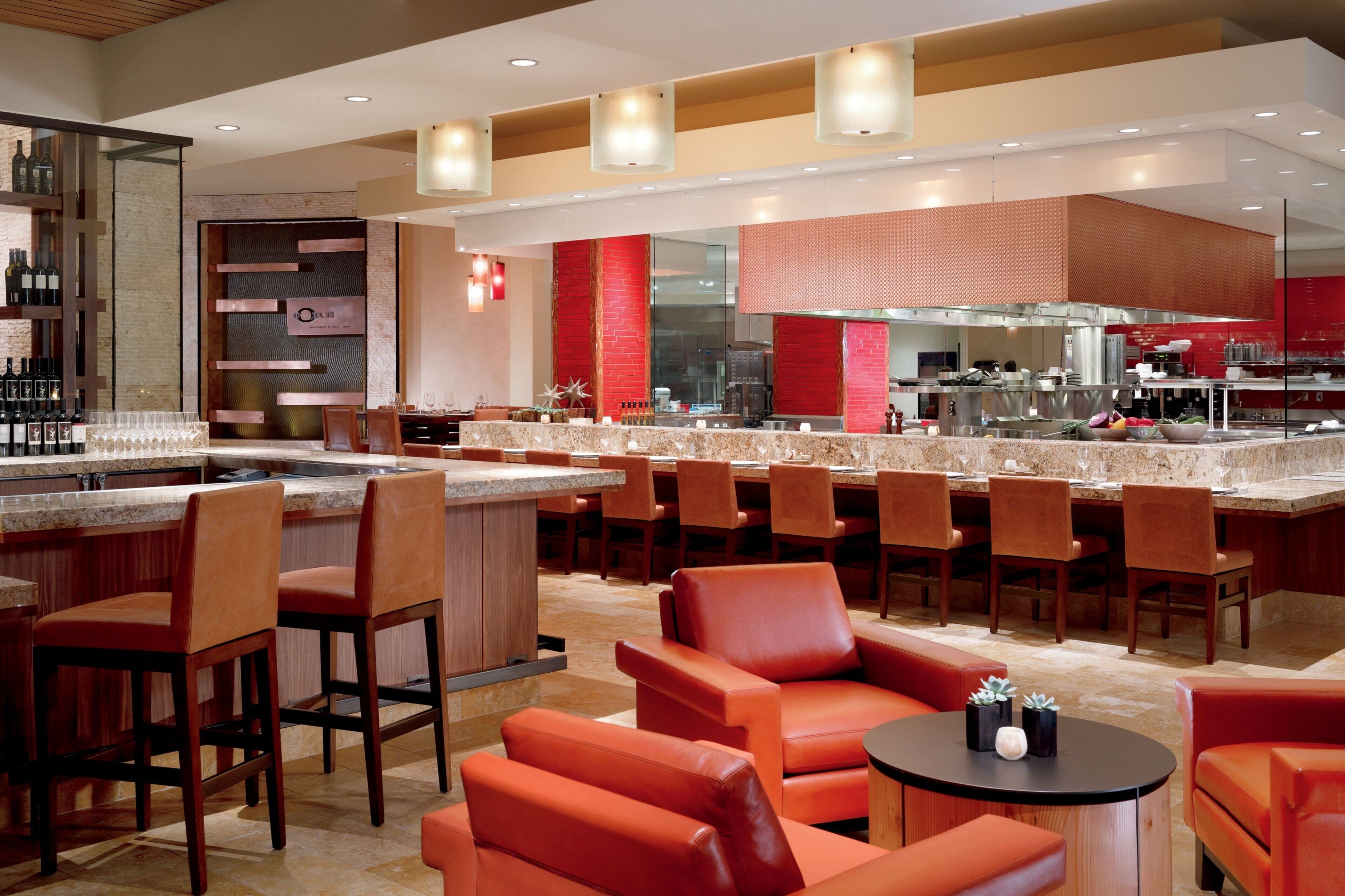 A modern bar area with seating, a kitchen in the background, and a red accent wall.
