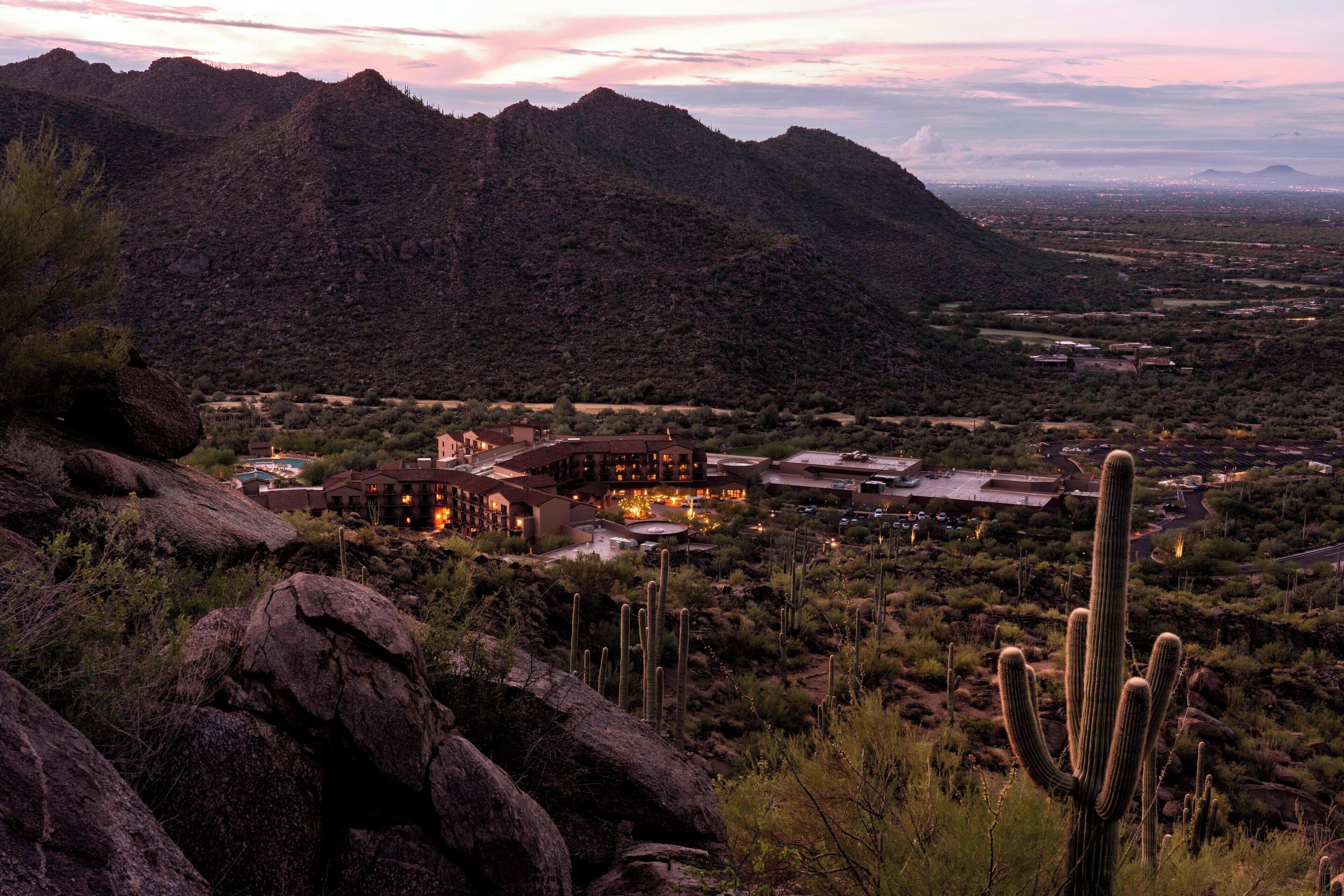 A desert landscape with mountains, a large building with multiple rooms, and cacti.