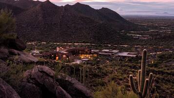 A desert landscape with mountains, a large building with multiple rooms, and cacti.
