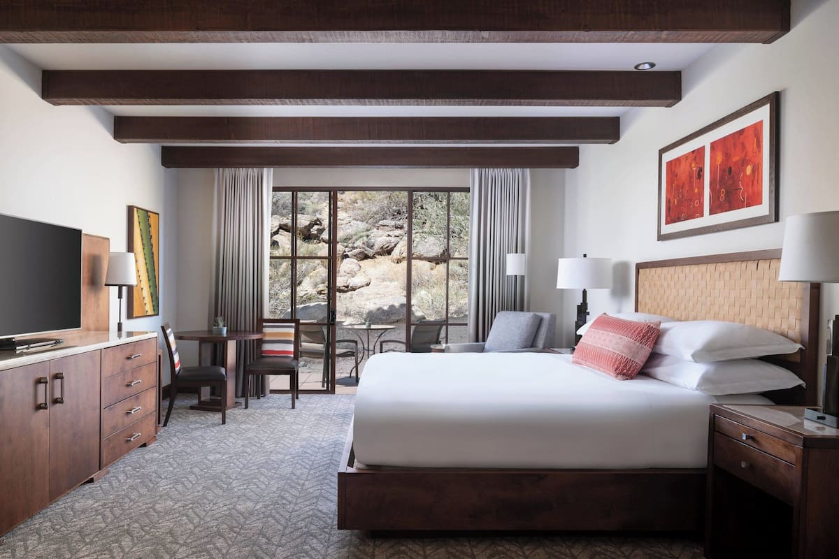 A hotel room with a large bed, a desk, a chair, and a television.