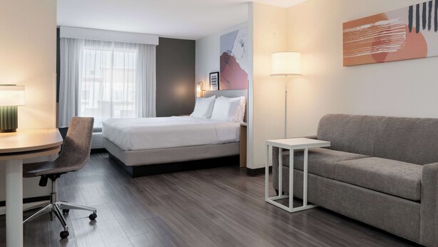 Een hotelkamer met een bed, bureau, stoel, bank en lamp.