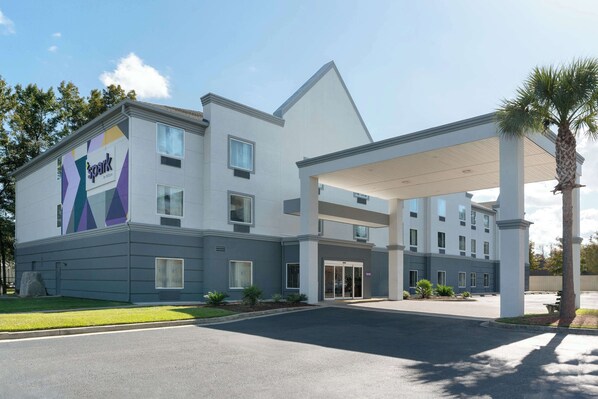 Moderni hotelli, jossa on selkeästi näkyvä «Spark by Hilton» -kyltti, katettu sisäänkäynti ja hyvin hoidettu nurmikko.