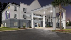 Een modern hotel met een overdekte ingang, meerdere verdiepingen en een goed verlichte gevel.