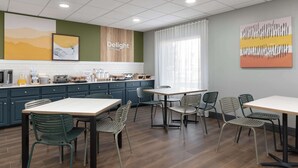 Een moderne keuken met een eethoek, met een groot eiland, groene stoelen en een aanrecht met apparatuur.
