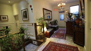 A spacious foyer with a grand staircase, a chandelier, and a red patterned rug. - Parc Suites Hotel (Montreal)