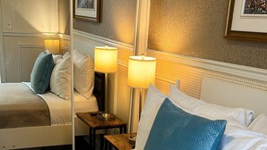 A hotel room with a large bed, two bedside lamps, a mirror, and a framed picture on the wall. - Parc Suites Hotel (Montreal)