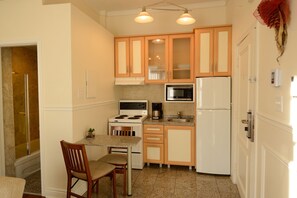 Una cocina compacta con muebles de madera, microondas, estufa y refrigerador.