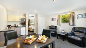 Una habitación de hotel compacta con kitchenette, comedor y sala de estar.
