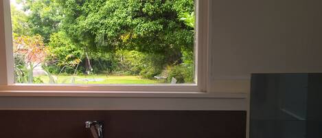 A kitchen with a stainless steel sink and a window overlooking a garden.