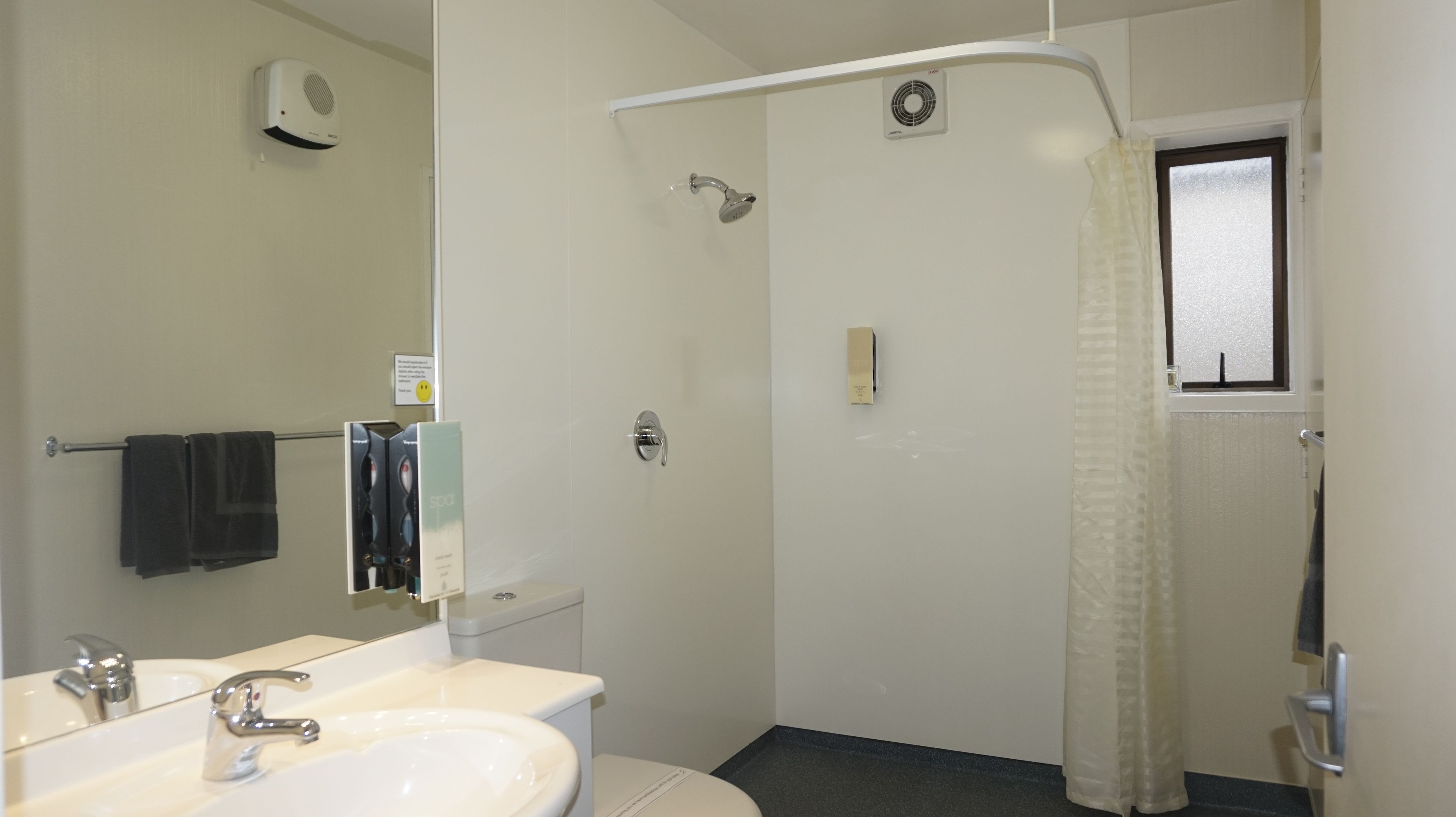 A bathroom with a sink, mirror, towel rack, shower, and toilet.