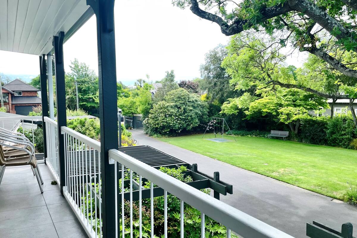 A covered porch with a view of a well-maintained lawn and trees.