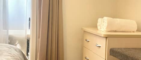 A hotel room with a bed, a dresser, and a window with curtains.