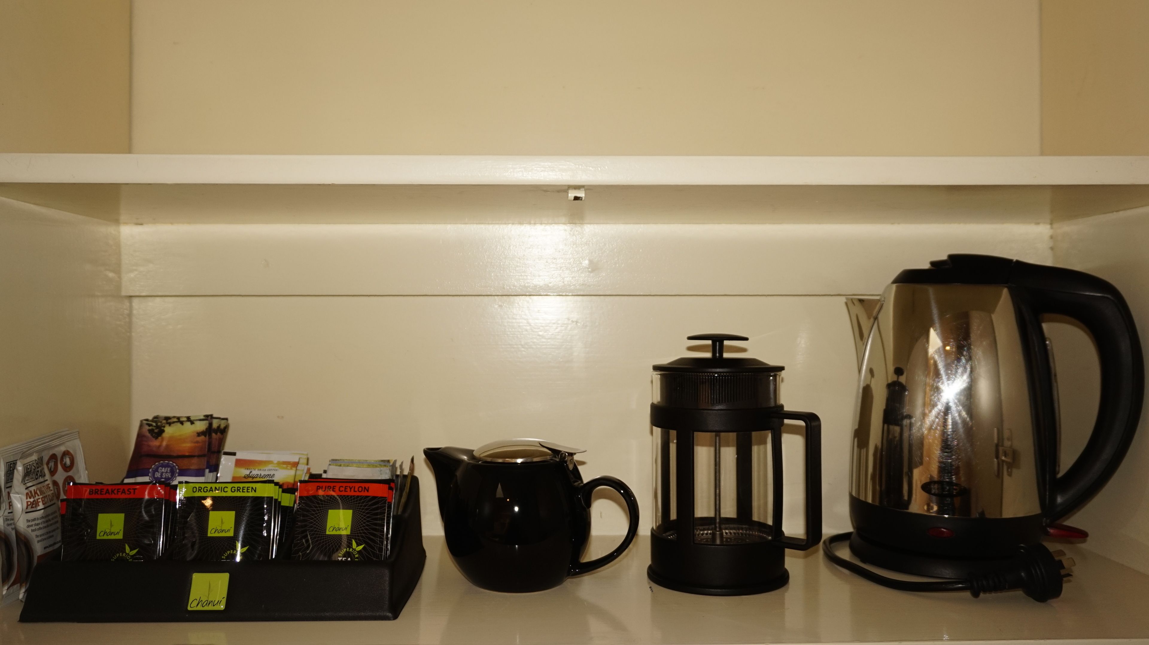 A kitchen counter with a coffee maker, a French press, and a coffee pod holder.