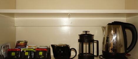 A kitchen counter with a coffee maker, a French press, and a coffee pod holder.