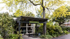 A reception area with a sign, a covered entrance, and a small outdoor seating area. - Ashleigh Court Motel-Christchurch Hagley Park (Christchurch)