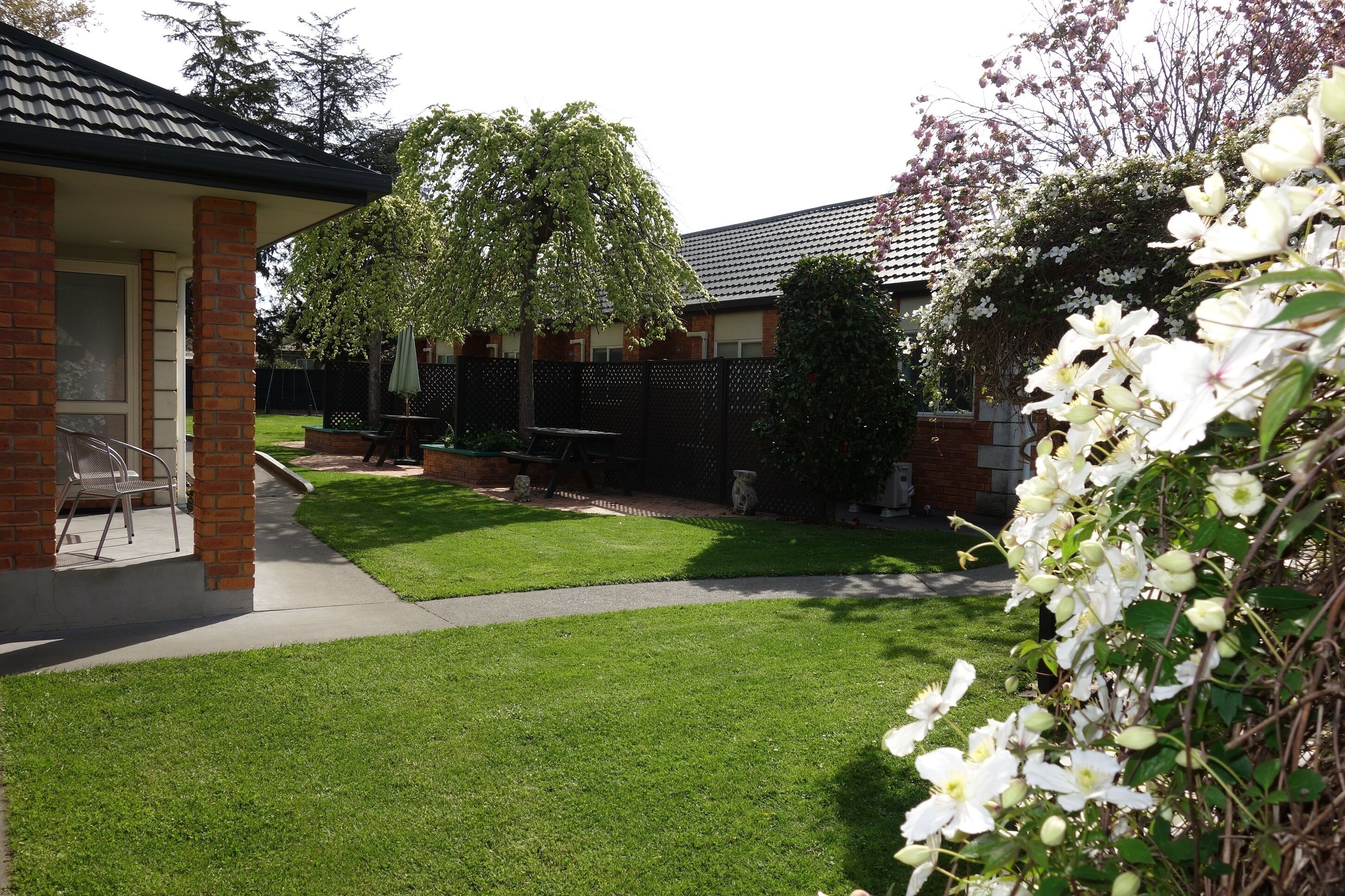 A well-maintained backyard with a lawn, patio furniture, and a brick building.