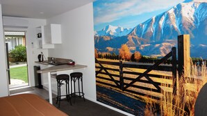 Een moderne keuken met een eetgedeelte, een groot raam en een muurschildering van een berglandschap.