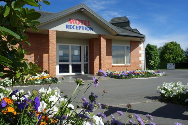 A motel reception building with a brick facade, large windows, and a sign above the entrance.