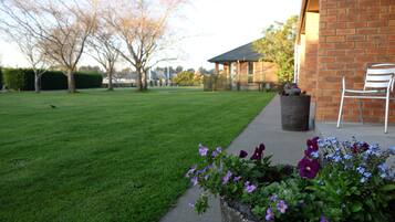 A well-maintained lawn, a brick building, and a seating area with a chair.