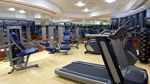A gym with Nautilus equipment, a treadmill, and mirrors on the walls.