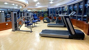 A gym with treadmills, weight machines, and a mirrored wall.