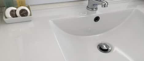 A modern bathroom with a white sink, chrome faucet, and a mirror above.