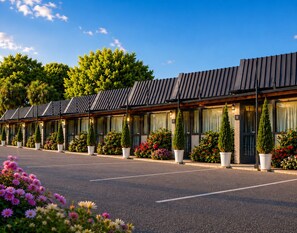 A row of hotel rooms with a modern design, large windows, and potted plants in front. - Gothic Heights Motel (Christchurch)