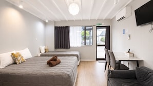 A hotel room with two beds, a desk, a chair, and a TV. - Gothic Heights Motel (Christchurch)