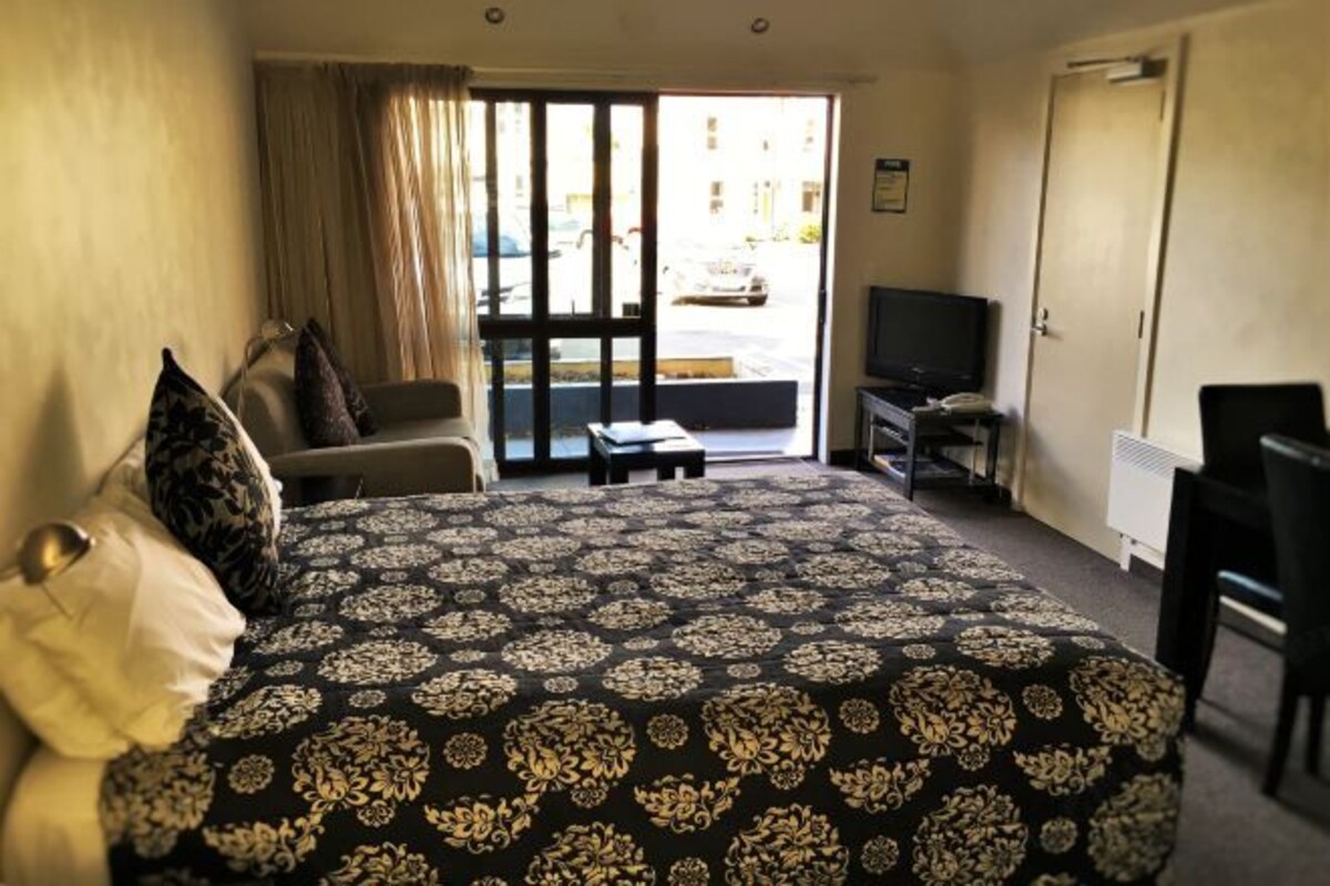 A hotel room with a large bed, a television, a desk, and a chair.