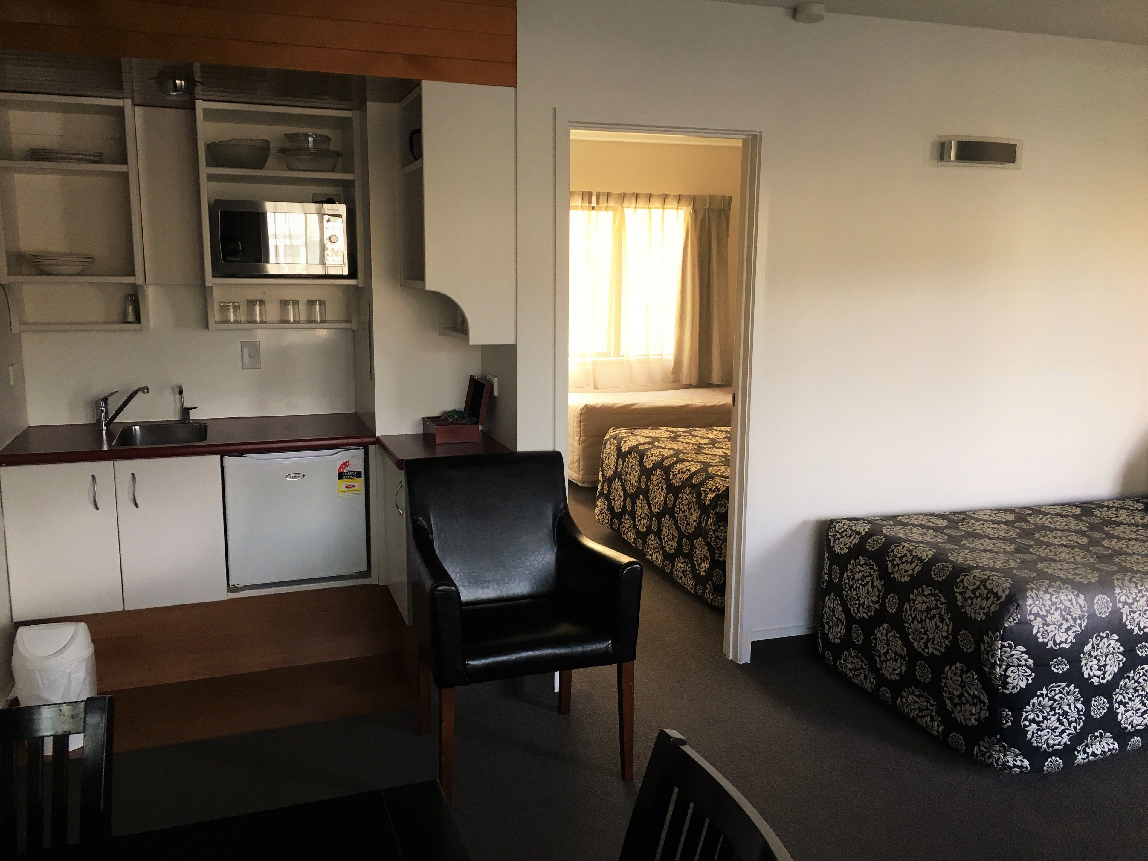 Quarto compacto com cozinha compacta, uma cama de solteiro e uma cadeira.