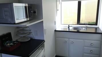A compact kitchen with a microwave, a sink, and a window.