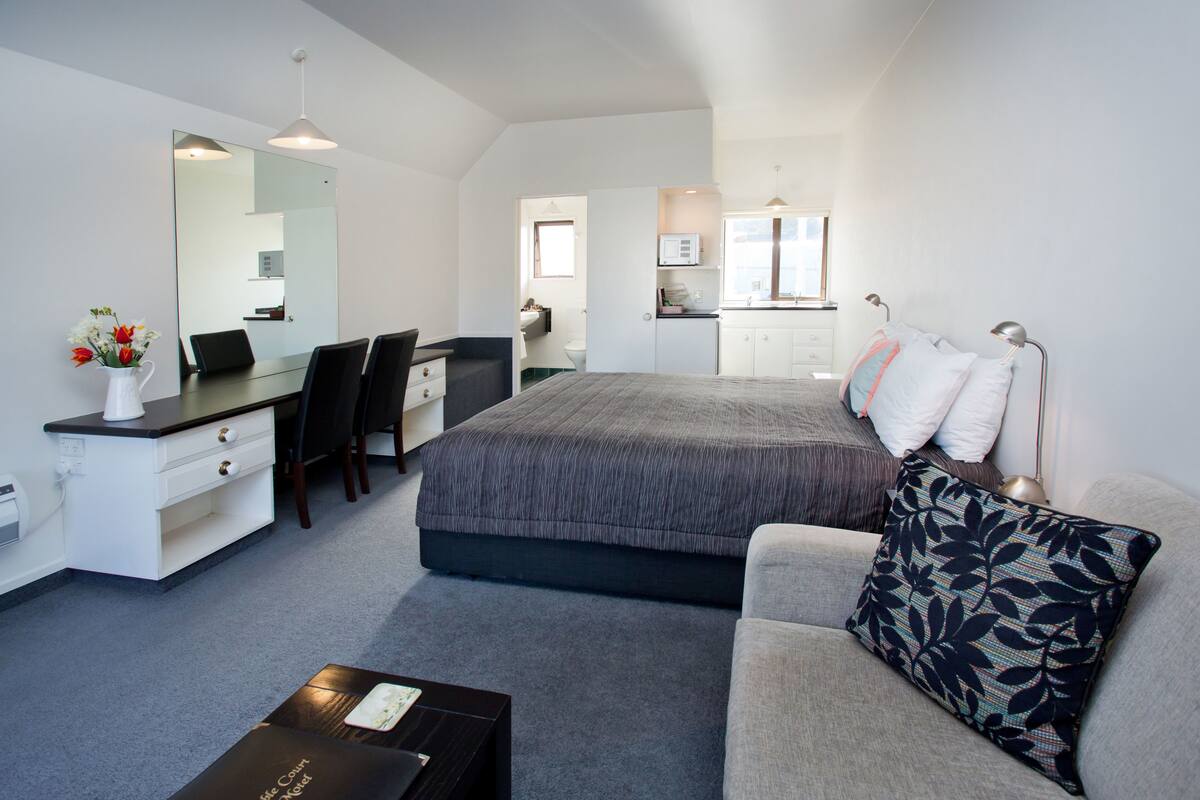 Ein modernes Hotelzimmer mit Bett, Schreibtisch, Stuhl, Sofa und Couchtisch.