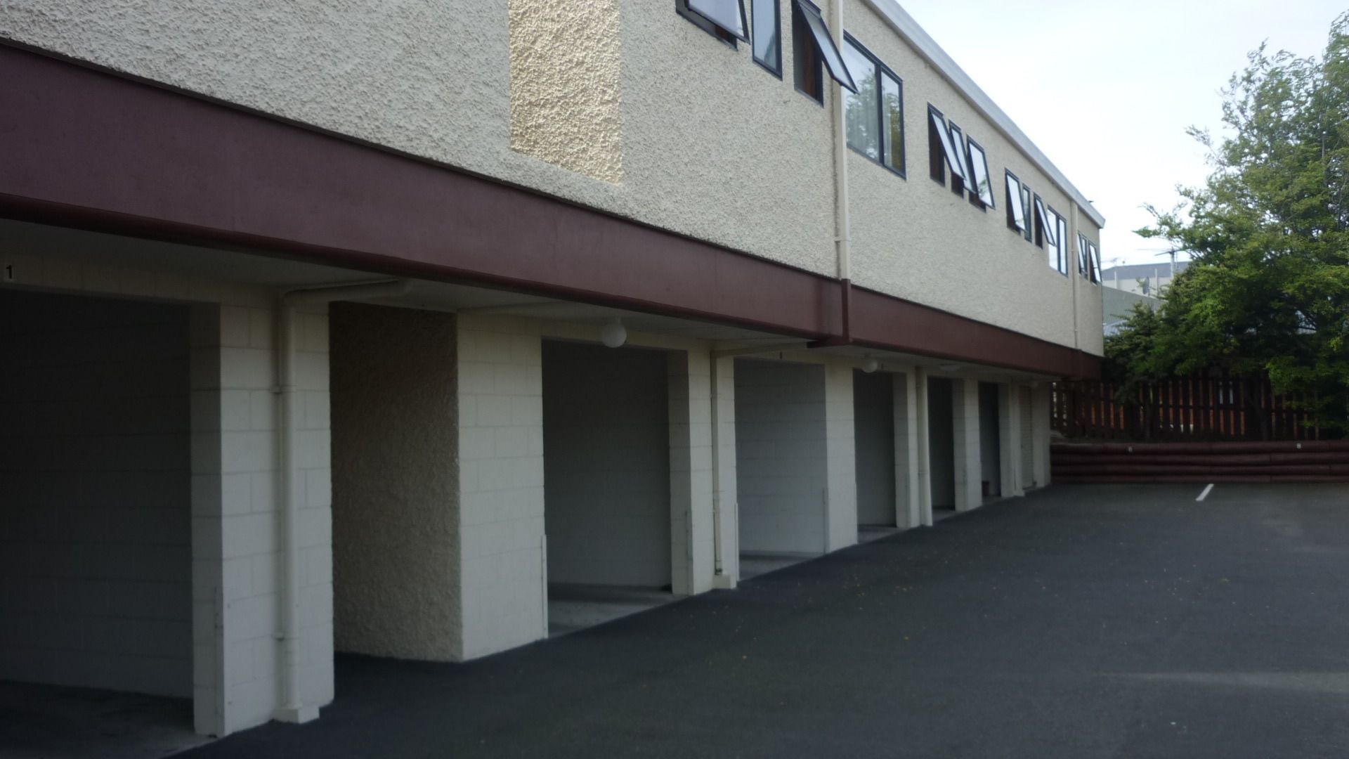 A building with a row of empty parking spaces and a covered walkway.