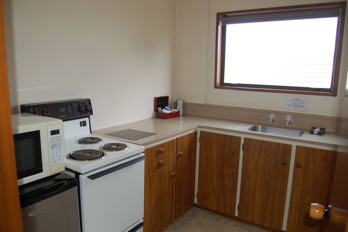 Una cocina compacta con microondas, estufa y pileta.