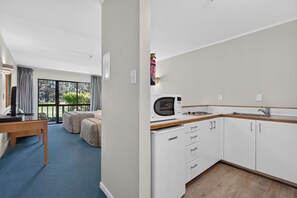 A modern kitchen with white cabinets, a microwave, and a sink. - Capital Lodge Motor Inn (Wellington)