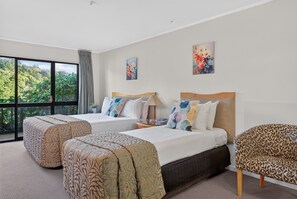 Habitación de hotel con dos camas, un ventanal grande y vistas al verdor.