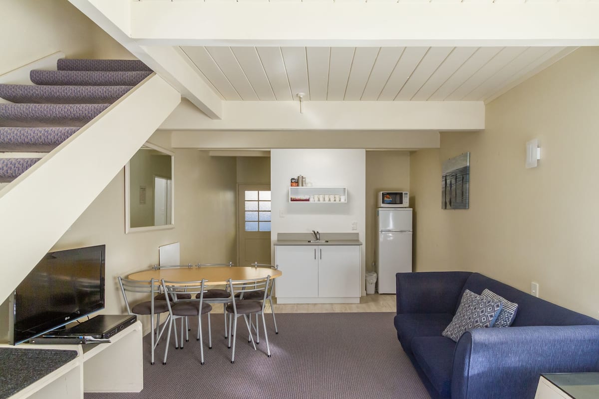 A compact living space with a dining area, kitchenette, and a staircase.