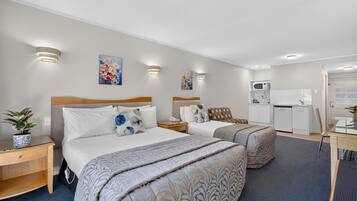 A hotel room with two beds, a kitchenette, and a small dining area.